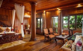 There is a living room with chairs and tables located in the center, adjacent to an open doorway at Ta Prohm Hotel & Spa