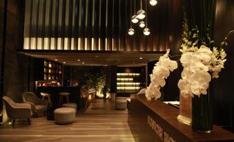 a hotel lobby with a wooden bar , several potted plants , and a large vase filled with white flowers at Boston Hotel