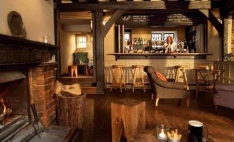 a cozy restaurant with wooden beams , a fireplace , and a bar area , inviting customers to relax at The Crown
