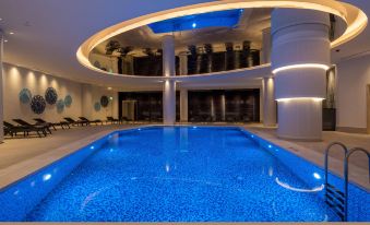a modern swimming pool with blue water , surrounded by white walls and a circular ceiling at Hilton Mall of Istanbul