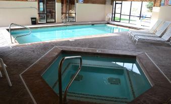 an indoor swimming pool with a hot tub , surrounded by chairs and tables , in a well - lit room at Daniels Summit Lodge