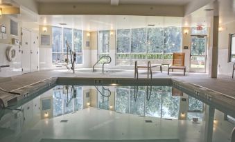 a large indoor swimming pool with a sun deck and chairs , surrounded by windows that offer views of the outdoors at Courtyard Philadelphia Bensalem