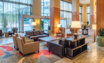 a modern hotel lobby with a large window , multiple couches , chairs , and tables arranged in a comfortable seating area at Hilton Vancouver Washington