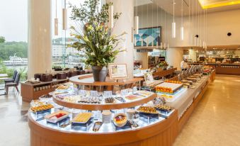 a large dining table filled with an assortment of food items , including various types of desserts and pastries at New Akan Hotel
