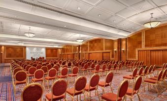 a large conference room with rows of red chairs arranged in an auditorium - style seating arrangement at Sheraton Skyline Hotel London Heathrow