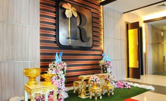 "a black and gold lobby with flowers , vases , and a large "" r "" sign on the wall" at Grand Ratchapruek Hotel