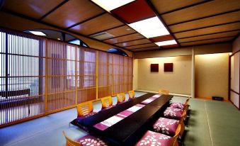 a dining room with a long wooden table and chairs arranged for a group of people at Biwako Ryokusuitei