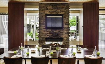 a dining room with a wooden table and chairs , along with a fireplace in the background at Novotel Queenstown Lakeside