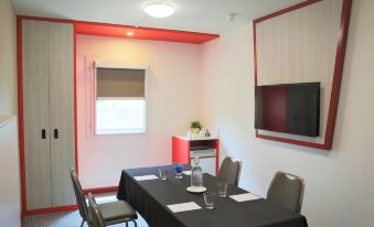 a small dining room with a table and chairs set up for a meal , and a tv mounted on the wall at Ibis Sydney Airport