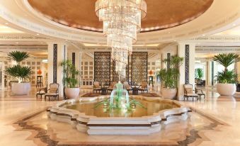 a large , well - lit hotel lobby with a crystal chandelier hanging from the ceiling and a fountain in the center at Dusit Thani Hua Hin