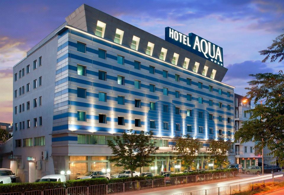 a large hotel building with a blue and white facade , situated on a city street at Aqua Hotel