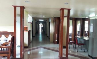a long hallway with wooden pillars on either side and a person standing at the end at Rawanda Resort Hotel