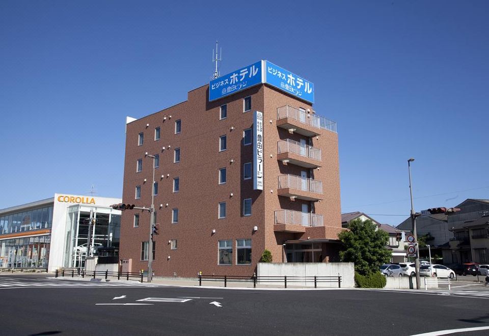 a brick building with a blue sign on top , located in a city setting with a street in front of it at Toyota Village