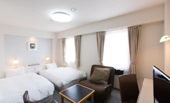 a modern hotel room with two beds , a chair , and a window , all set against white walls at Hotel Wing International Miyakonojo