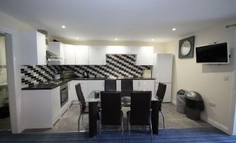 a modern kitchen and dining area with black and white checkered tiles on the walls , equipped with a dining table and chairs at Marine Apartment