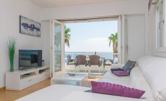 a living room with a couch , television , and sliding glass doors leading to an ocean view balcony at Cala Bona