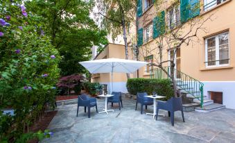 a courtyard with a table and chairs set up for outdoor dining , surrounded by lush greenery at NH Geneva City