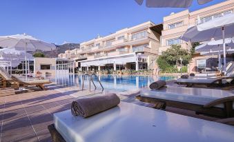 a large swimming pool with white lounge chairs and umbrellas in front of a resort at Happy Hotel Kalkan