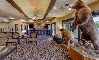 a large teddy bear is sitting on a couch in a room with chairs and a chandelier at Best Western Dunmar Inn