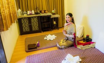 a woman in traditional thai clothing is sitting on a bed with her hands folded at Mammoth Resort