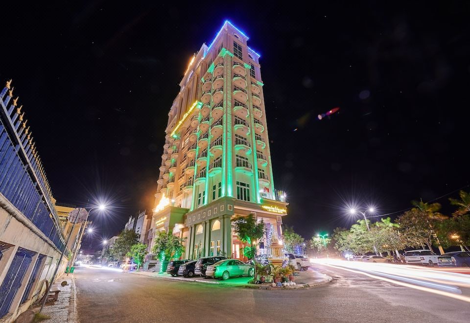 a tall building with many windows lit up at night , surrounded by cars and traffic at Lbn Asian Hotel