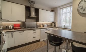 a modern kitchen with white cabinets and a stainless steel countertop , equipped with various appliances and utensils at Carmel Apartments