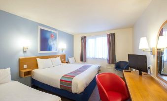 a modern hotel room with two beds , a red chair , and a desk , all neatly arranged at Travelodge Kendal