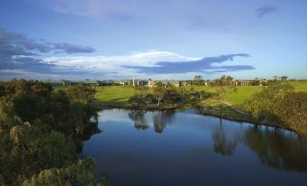 a serene landscape of a river flowing through a grassy field , with a house in the distance at Aitken Hill