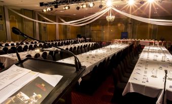 a large dining room filled with long tables covered in white tablecloths , ready for a formal event at Hotel Grand Chancellor Launceston