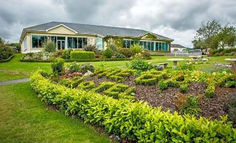 a house surrounded by a lush green garden , with various plants and flowers in the yard at Arklow Bay Hotel