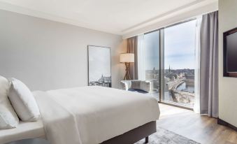 a hotel room with a large bed , a couch , and a window overlooking a cityscape at Radisson Blu Waterfront Hotel, Stockholm