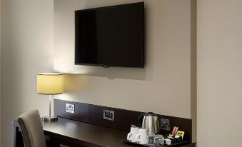 a hotel room with a flat - screen tv mounted on the wall above a coffee table at Premier Inn London Romford West