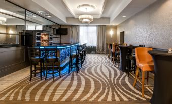a modern lounge area with a bar , stools , and a zebra print carpet , along with a window and ceiling light at Crowne Plaza Suffern-Mahwah, an IHG Hotel