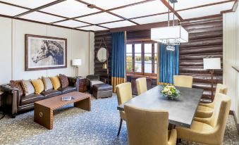 a living room with a wooden ceiling , a couch , a dining table , chairs , and a tv at Fairmont le Chateau Montebello