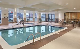 a large swimming pool with a diving board and lounge chairs in the background , surrounded by windows at Hilton Garden Inn Akron