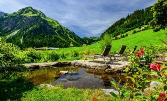 a serene mountainous landscape with green hills , clear blue water , and two lounge chairs in the foreground at Hotel Steinbock