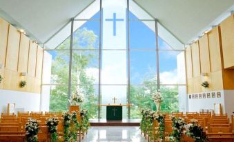a church interior with wooden pews , greenery , and a large window , providing a serene view of the surrounding scenery at Arcadia