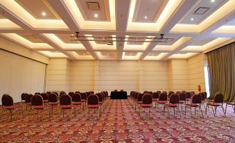 a large , empty conference room with rows of red and black chairs arranged in an orderly fashion at DiplomaticHotel