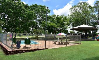 a beautiful outdoor setting with a swimming pool , umbrellas , and picnic tables under a clear blue sky at Hillview Motel