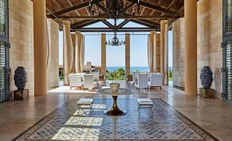 a spacious , elegant living room with a large table in the center and multiple chairs surrounding it at The Romanos, a Luxury Collection Resort, Costa Navarino