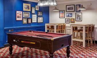 a pool table is in the middle of a room with blue walls and red checkered floor at Holiday Inn Leeds - Garforth