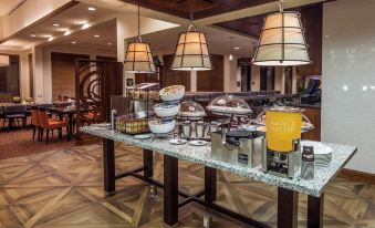a buffet table with various food items and drinks , including pastries , fruits , and beverages , is set up in a restaurant at Hilton Garden Inn Uniontown