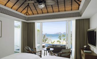a bedroom with a view of the ocean through a large window , surrounded by chairs and tables at Banyan Tree Krabi