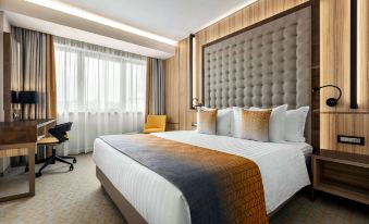a large bed with a wooden headboard and white linens is in a hotel room at Ramada by Wyndham Ramnicu Valcea