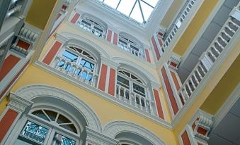 a tall , white and yellow building with arched windows and balconies , under a glass ceiling at Hotel Inglaterra