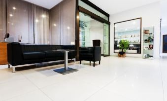 a modern office lobby with white tiles , a black couch , and a large glass wall at Hotel Fontana Plaza