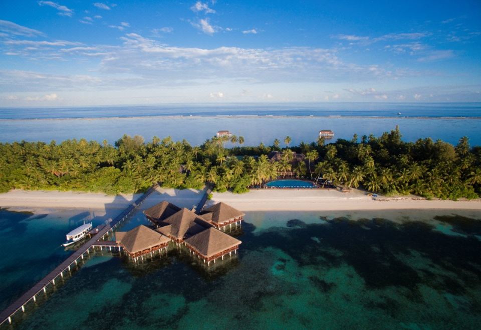 aerial view of a tropical island with a group of small houses surrounded by water , including a hotel on the beach at Medhufushi Island Resort