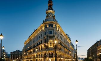 a large , ornate building with a clock tower is lit up at night in a city street at Four Seasons Hotel Madrid