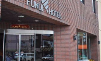 the entrance to the fuku hotel with cars parked outside and a sign above the door at Fukui Hotel