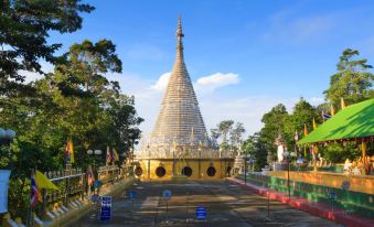 a large , golden pagoda surrounded by trees and benches , with blue barriers in front of it at Asian Hotel